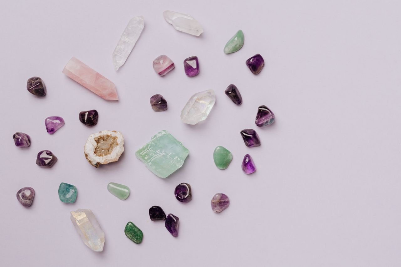 A collection of various crystals and gemstones arranged on a minimalist light surface.
